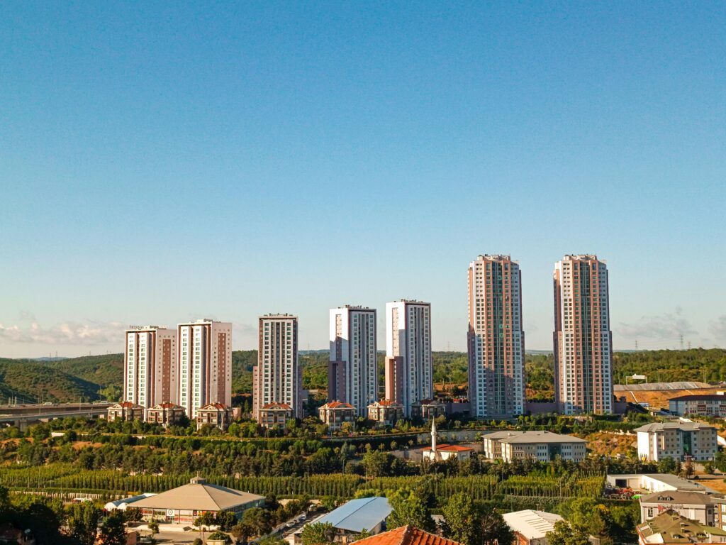 Aerial view of urban skyscrapers surrounded by greenery on a bright, clear day.